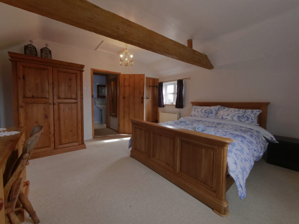 Holiday cottage bedroom with a wooden double bed, wardrobe