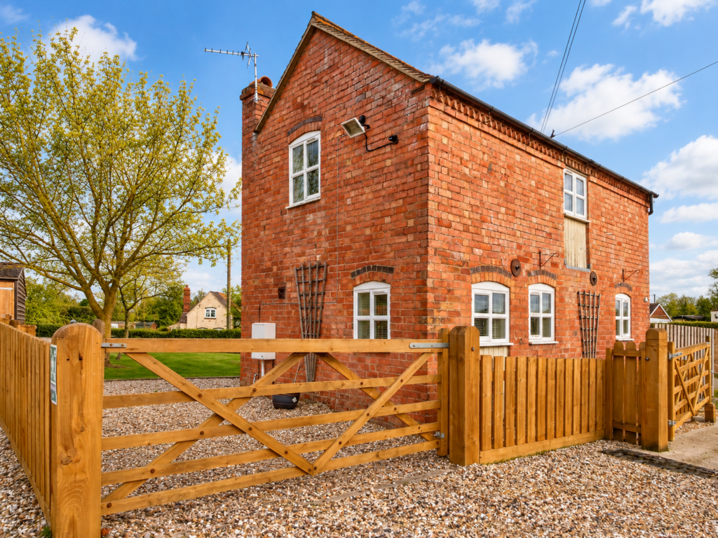 Red-brick holiday cottage behind wooden gates