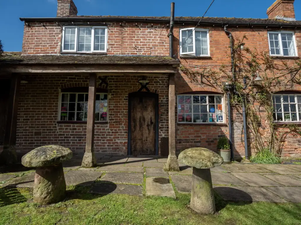Front porch of The Butchers Arms with staddle stones on the lawn
